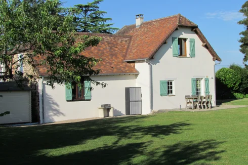 Cottage from the rear.  Small gravel terrace with table and chairs for guests outside dining.