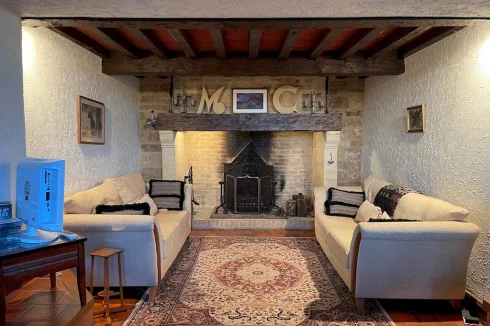 The snug, located two steps down from the salon, features a grand fireplace and a mezzanine above provides an elevated space for a reading nook or office.