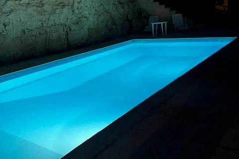 At night the pool is beautifully illuminated against a limestone wall, creating a stunning and tranquil ambiance.